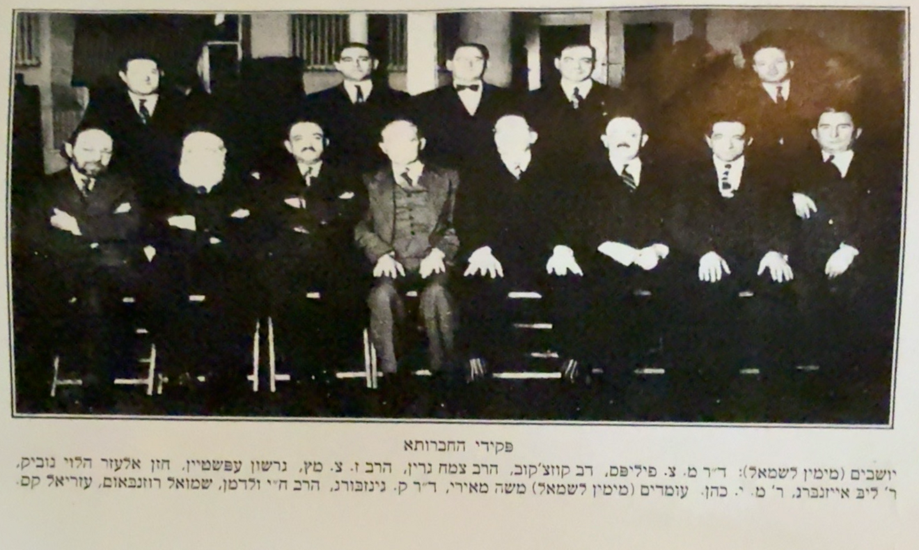Historical group photograph with its original Hebrew caption visible; Dov Bear Kasachkoff is believed by the family to be seated in the front row, second from the left.